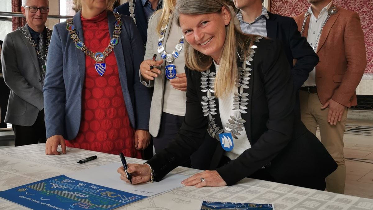 Ordfører Lene Conradi signerer erklæring med en kø av ordførere bak seg. 