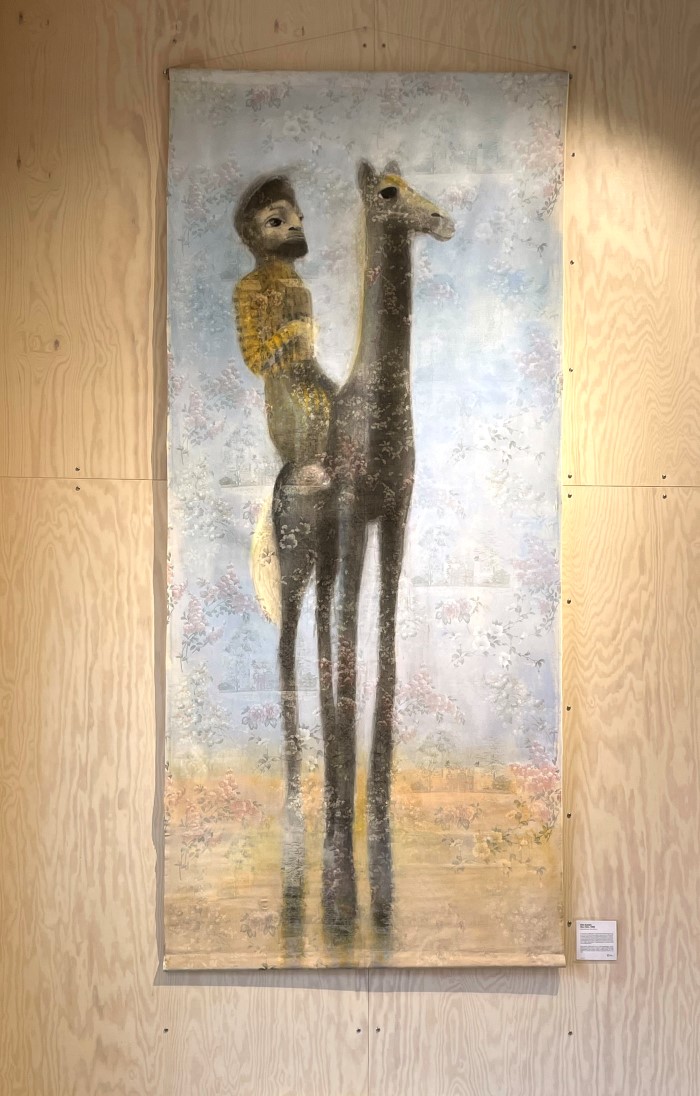 Et stort maleri av en mann på ryggen til en lama.
